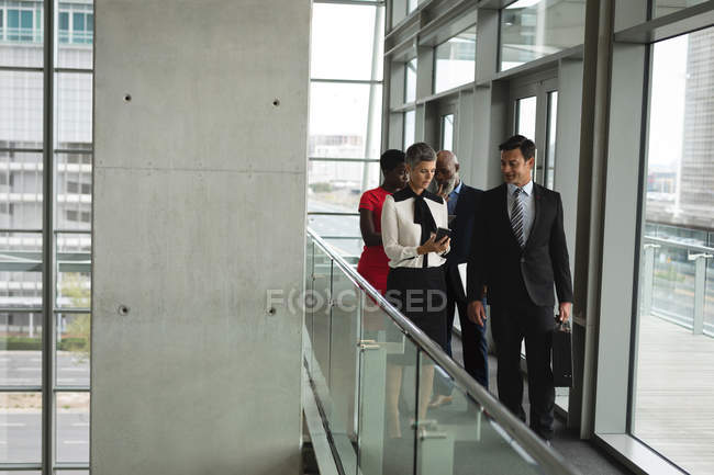 Groupe de gens d'affaires ayant une discussion tout en marchant dans le couloir au bureau — Photo de stock