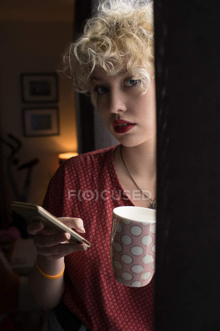 Portrait of young woman using mobile phone at home — Stock Photo
