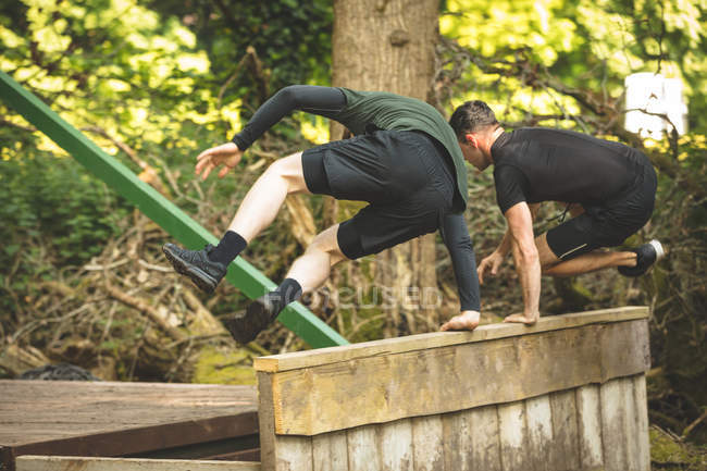Dois homens a exercitar-se em pista de obstáculos no campo de treino — Fotografia de Stock