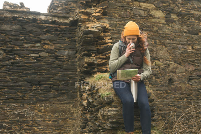 Schöne Wanderin beim Kaffeetrinken während sie die Karte liest — Stockfoto