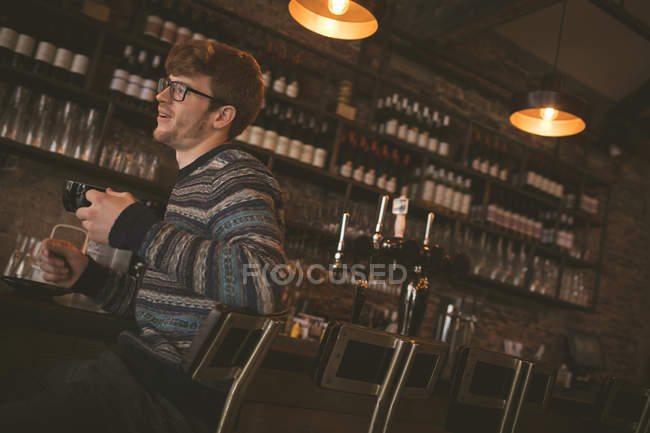 Молодий чоловік має каву, сидячи за барною стійкою — стокове фото