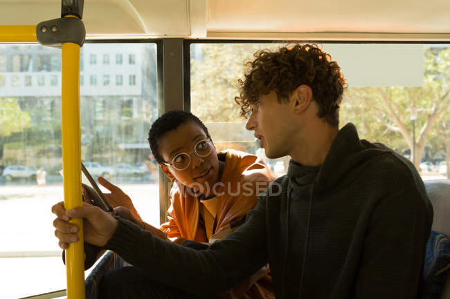 Hombre y mujer interactuando entre sí mientras viajan en el autobús - foto de stock