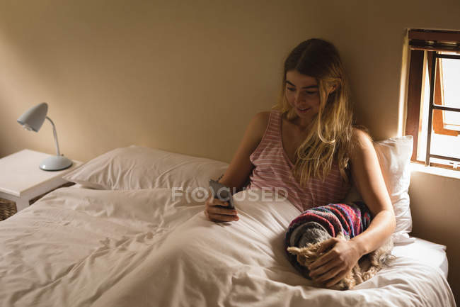 Mädchen mit Hund benutzt Handy im Schlafzimmer zu Hause — Stockfoto