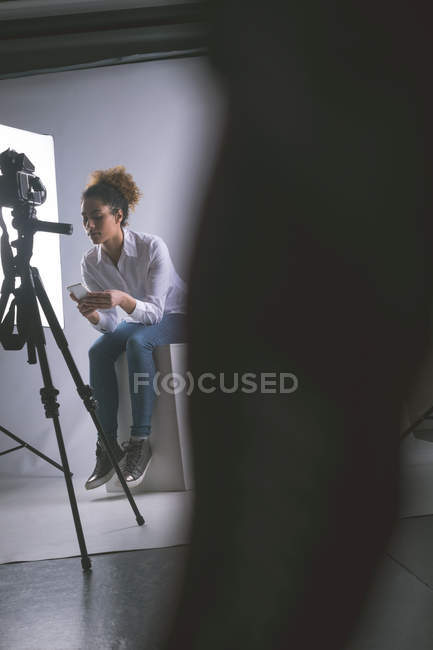 Жінка-фотограф використовує мобільний телефон у фотостудії — стокове фото