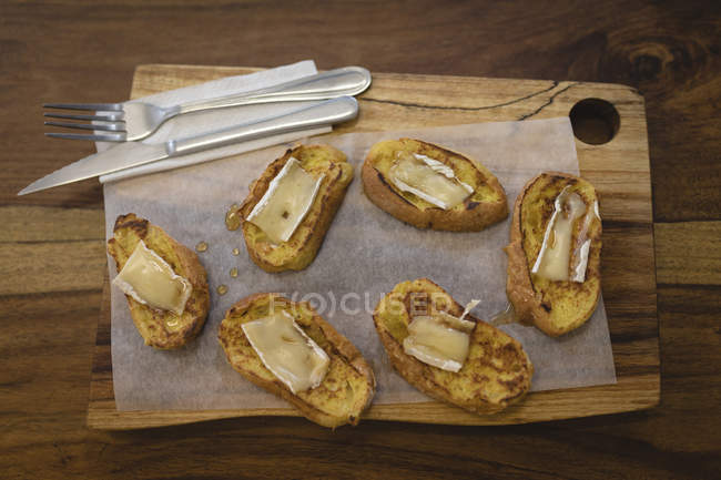 Pão com queijo servido em uma tábua de madeira em um café — Fotografia de Stock