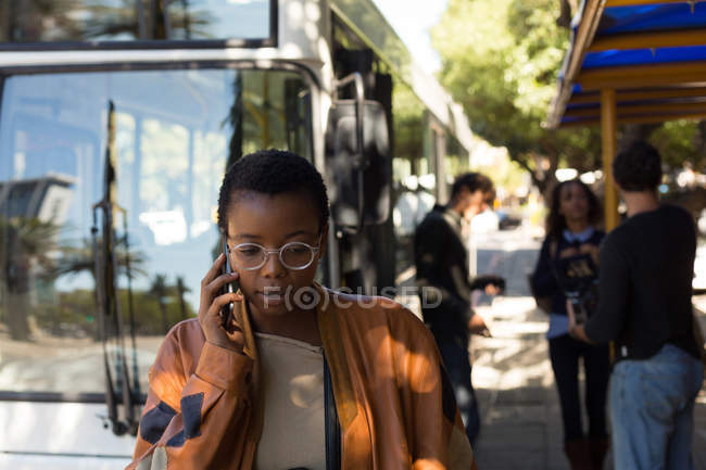 Woman talking on mobile phone at bus stop — Stock Photo