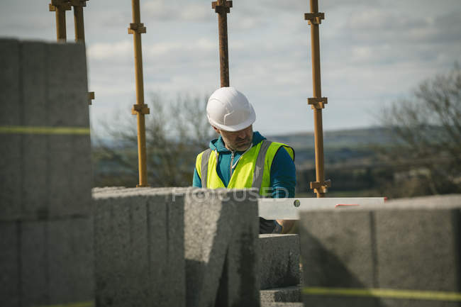 Ingenieur bei Niveaukontrolle an der Wand auf Baustelle — Stockfoto