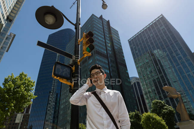 Чоловік розмовляє по мобільному телефону в місті в сонячний день — стокове фото