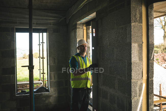 Ingénieur effectuant une vérification de niveau sur le mur sur le chantier de construction — Photo de stock