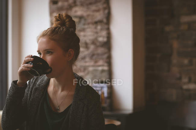 Mujer pensativa tomando café en la cafetería - foto de stock