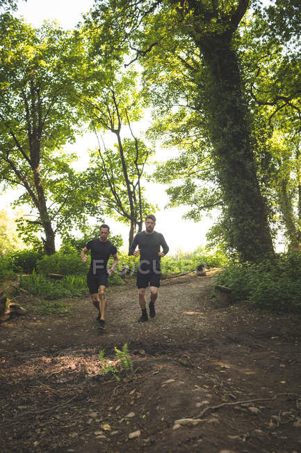 Dois homens a correr juntos num acampamento num dia ensolarado — Fotografia de Stock
