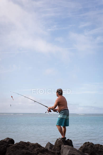Visão traseira de pescador que pesca em uma praia — Fotografia de Stock