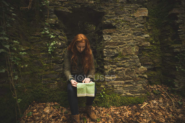 Caminante mujer de pelo rojo leyendo un mapa en el bosque - foto de stock