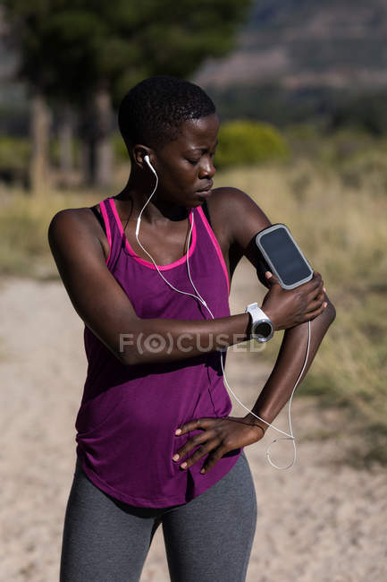 Primer plano de la atleta femenina escuchando música desde el reproductor de mp3 smartphone - foto de stock