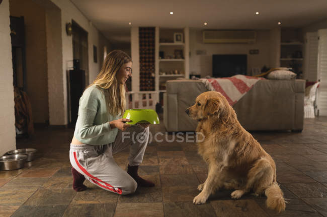 Дівчина-підліток годує свого собаку вдома — стокове фото
