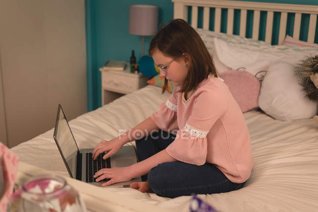 Ragazza utilizzando il computer portatile in camera da letto a casa — Foto stock