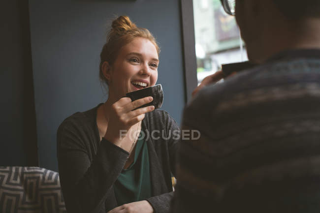 Jeune couple souriant prenant un café au café — Photo de stock