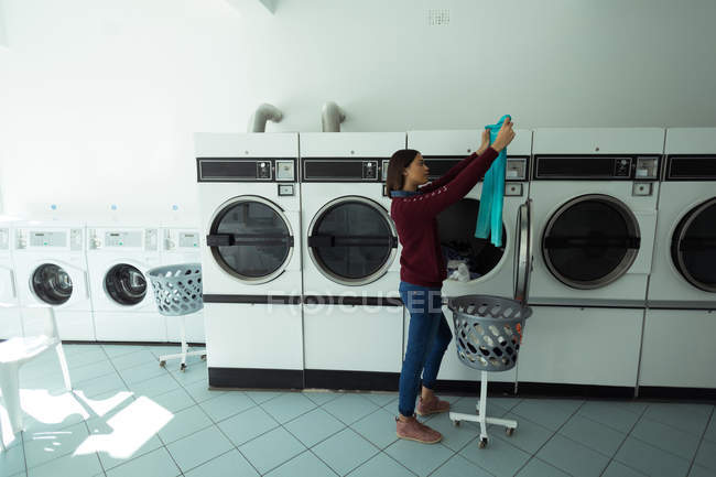 Young woman checking her clothes at laundromat — Stock Photo