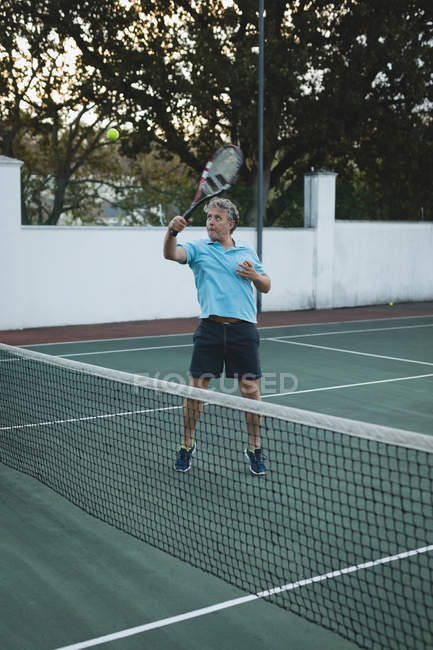 Side view of senior man playing tennis in tennis court — Stock Photo