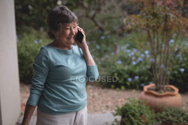 Старша жінка розмовляє по мобільному телефону на задньому дворі — стокове фото