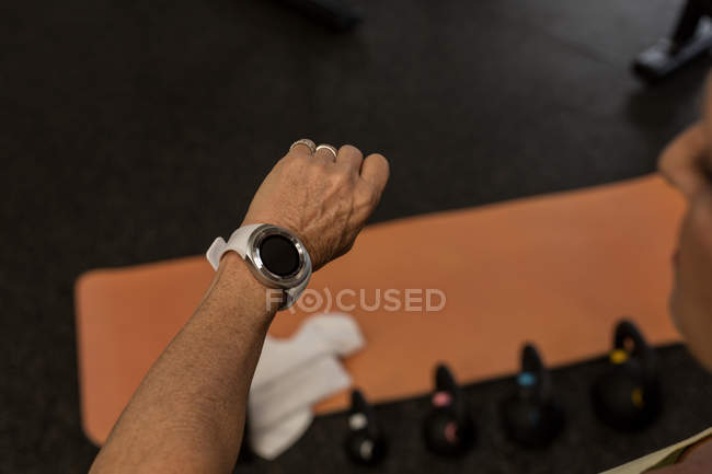 Behinderte Frau checkt Zeit auf Smartwatch im Fitnessstudio — Stockfoto