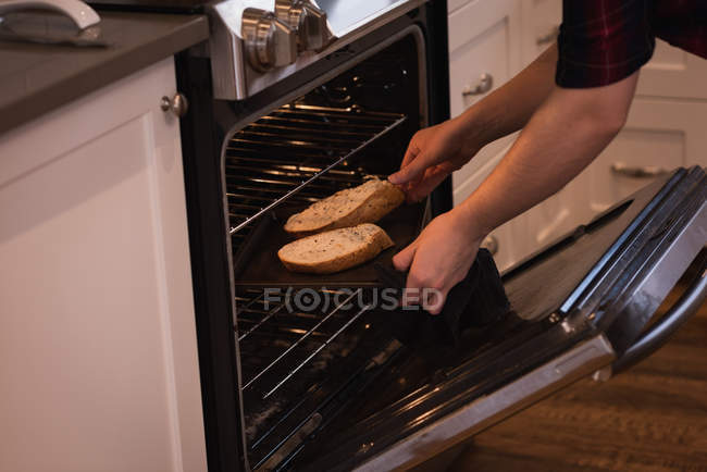 Femme mettre tranche de pain à l'intérieur de la owen dans la cuisine à la maison — Photo de stock
