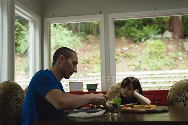 Pai e filha tendo juntos pizza em casa — Fotografia de Stock