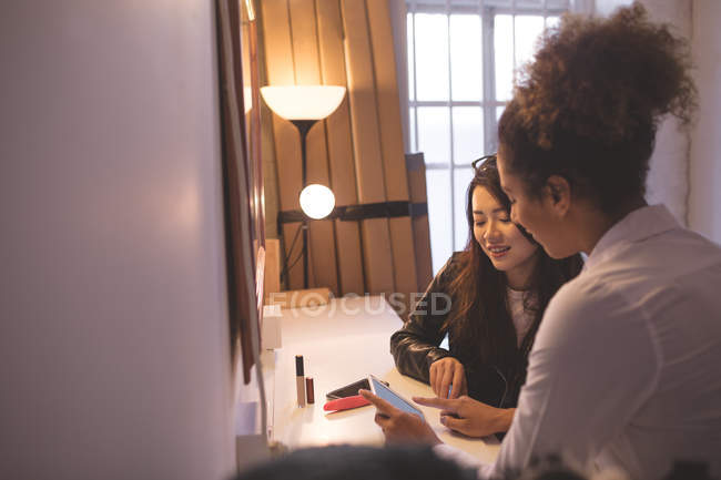 Femme photographe et mannequin utilisant une tablette numérique dans un vestiaire — Photo de stock