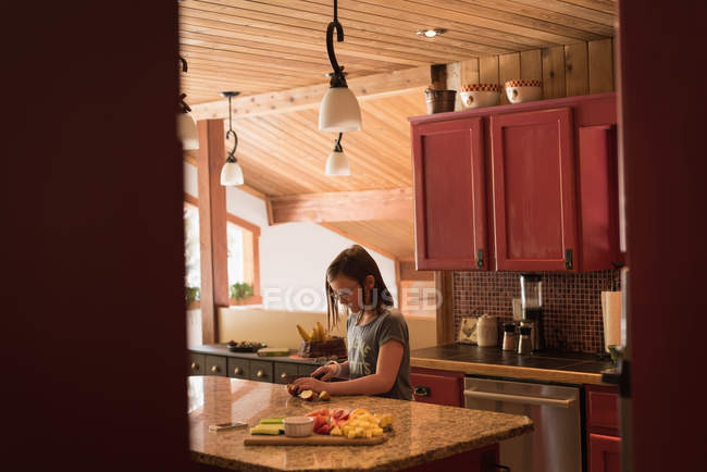 Girl cutting fruit salad in kitchen at home — Stock Photo