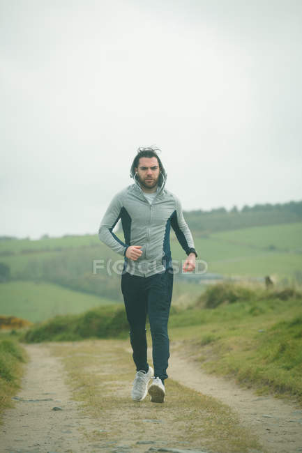 Fit man jogging through landscape — Stock Photo