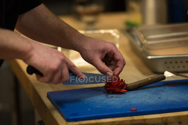 Мужчина шеф-повар режет фрукты на кухне в ресторане — стоковое фото