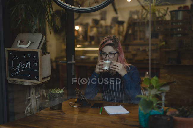 Молода жінка п'є каву в кав'ярні — стокове фото