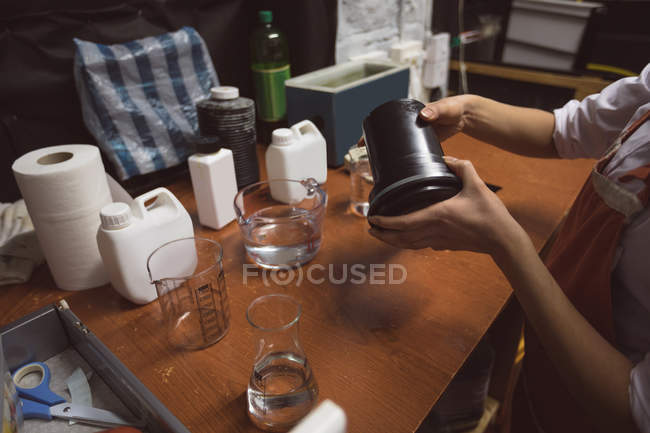 Female photographer cleaning a lens cover with liquid in photo studio — Stock Photo