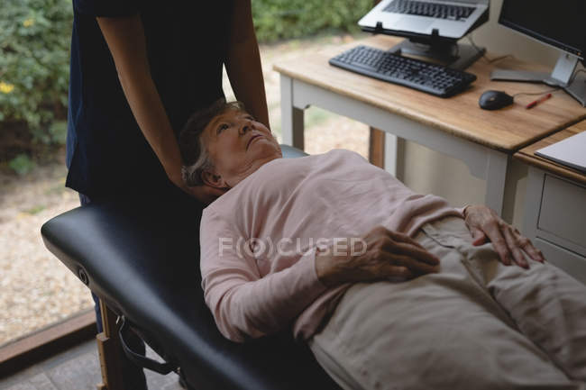 Gros plan du physiothérapeute donnant un massage de la tête à une femme âgée — Photo de stock