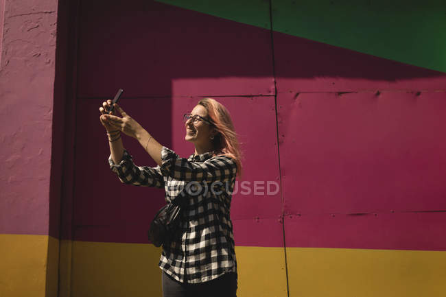 Young woman taking a selfie on mobile phone at the pavement — Stock Photo