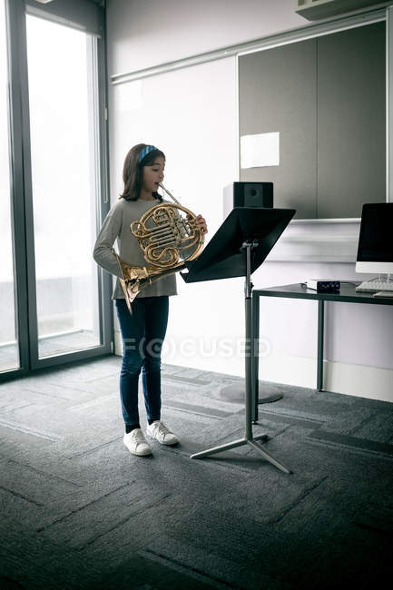 Чарівна школярка грає французький ріг в музичній школі — стокове фото