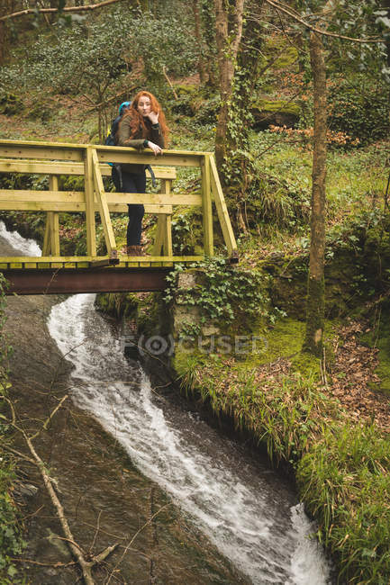 Bella escursionista femminile con zaino guardarsi intorno nella foresta — Foto stock