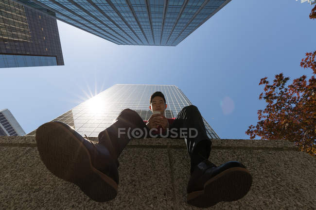 Low angle view of man using mobile phone in the city — Stock Photo