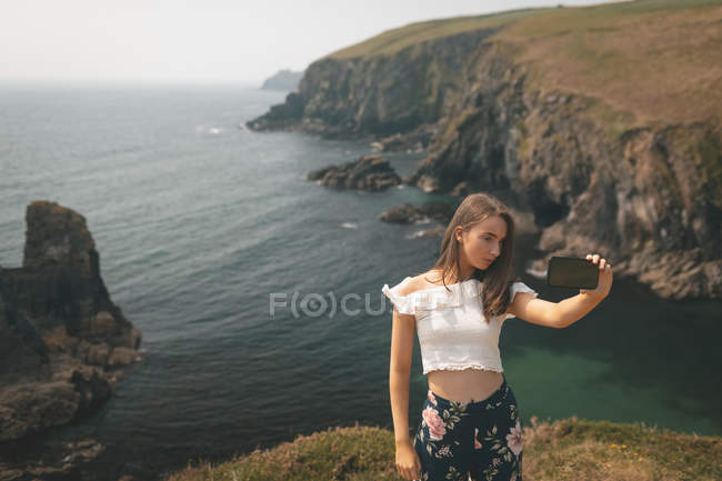 Beautiful woman taking selfie edge of the cliff — Stock Photo