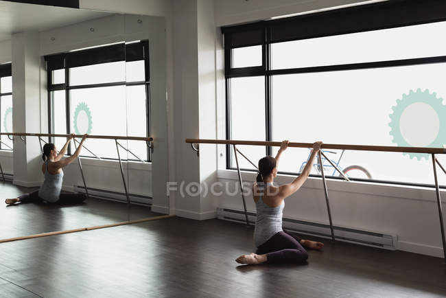 Young woman stretching on the barre at the gym — Stock Photo