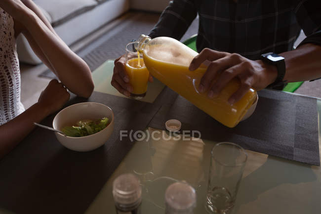 Casal ter suco de laranja na sala de estar em casa — Fotografia de Stock