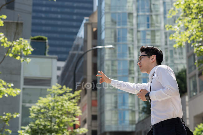 Un jeune homme appelle un taxi dans la rue — Photo de stock