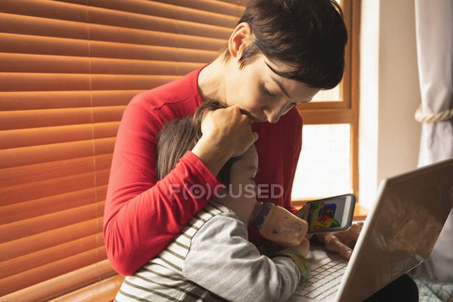 Primo piano madre e figlio seduti con un computer portatile a casa — Foto stock