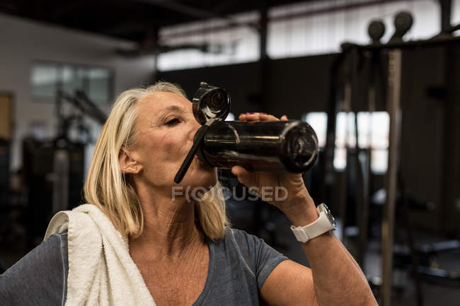 Disabili donna matura bere acqua in palestra — Foto stock