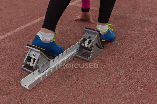 Low section of female athletic ready for the race at running track — Stock Photo