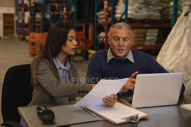 Personnel interagissant les uns avec les autres sur des documents en entrepôt — Photo de stock