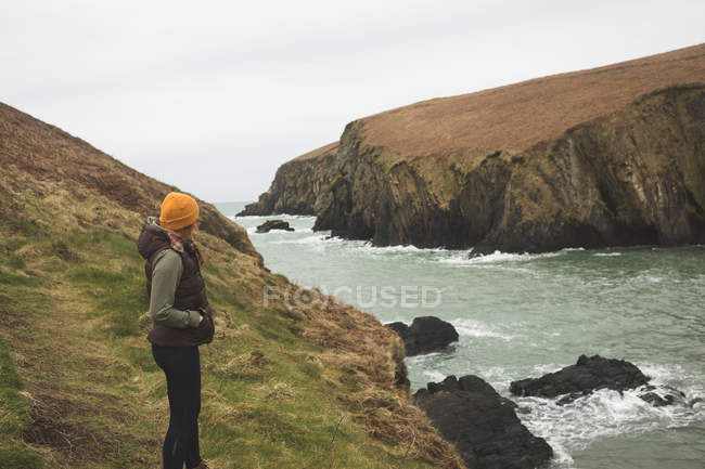 Vista lateral del excursionista femenino de pie cerca de la costa - foto de stock