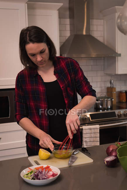 Donna mescolando succo di limone in cucina a casa — Foto stock