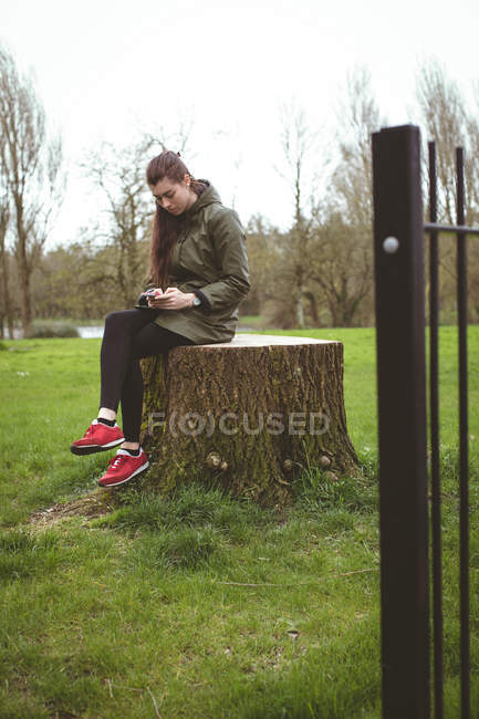 Beautiful woman using mobile phone in park — Stock Photo