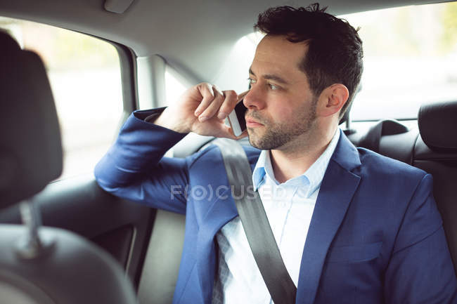 Businessman talking on mobile phone in a modern car — Stock Photo